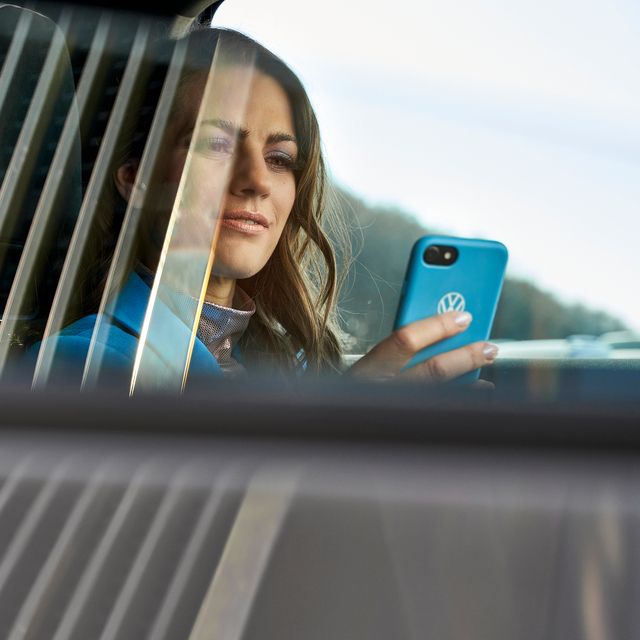 Frau schaut auf ein Handy im Auto