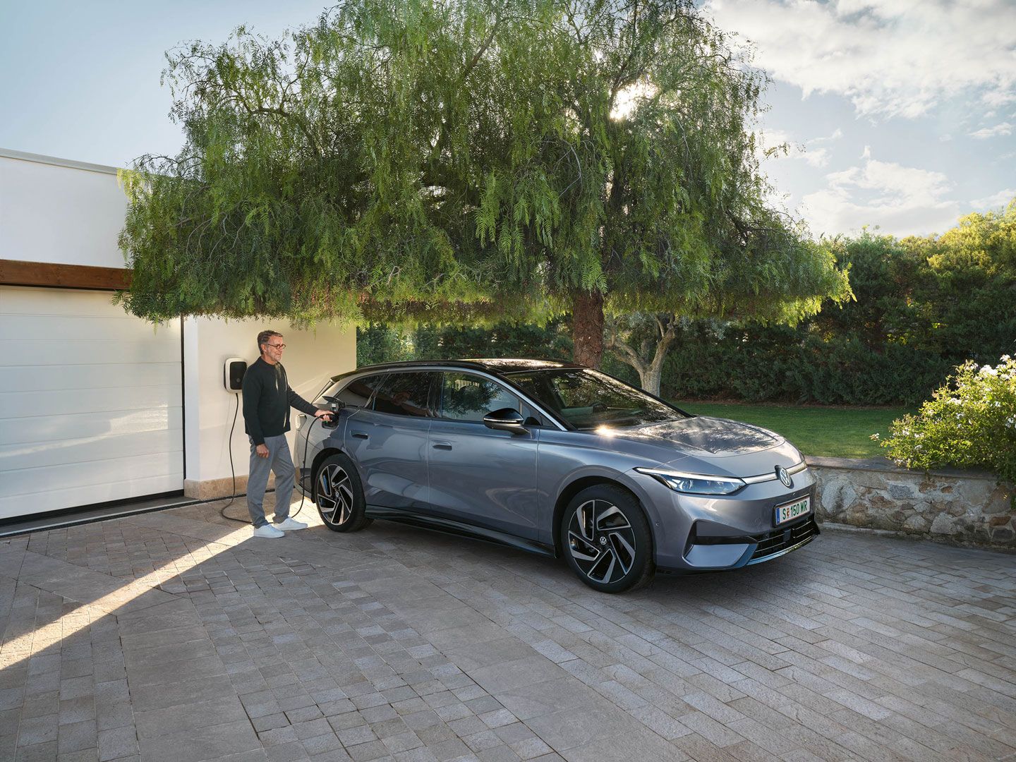 Mann lädt seinen VW ID.7 Tourer über eine Wallbox vor seiner Garage