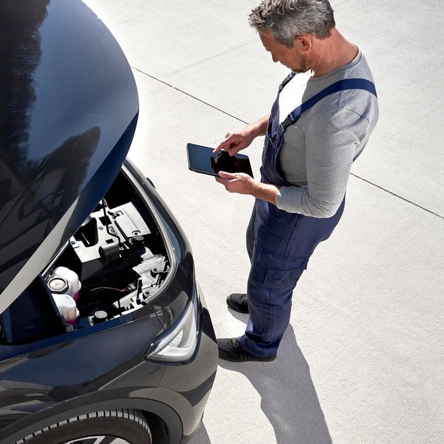 Volkswagen Service Techniker vor geöffneter Motorhaube
