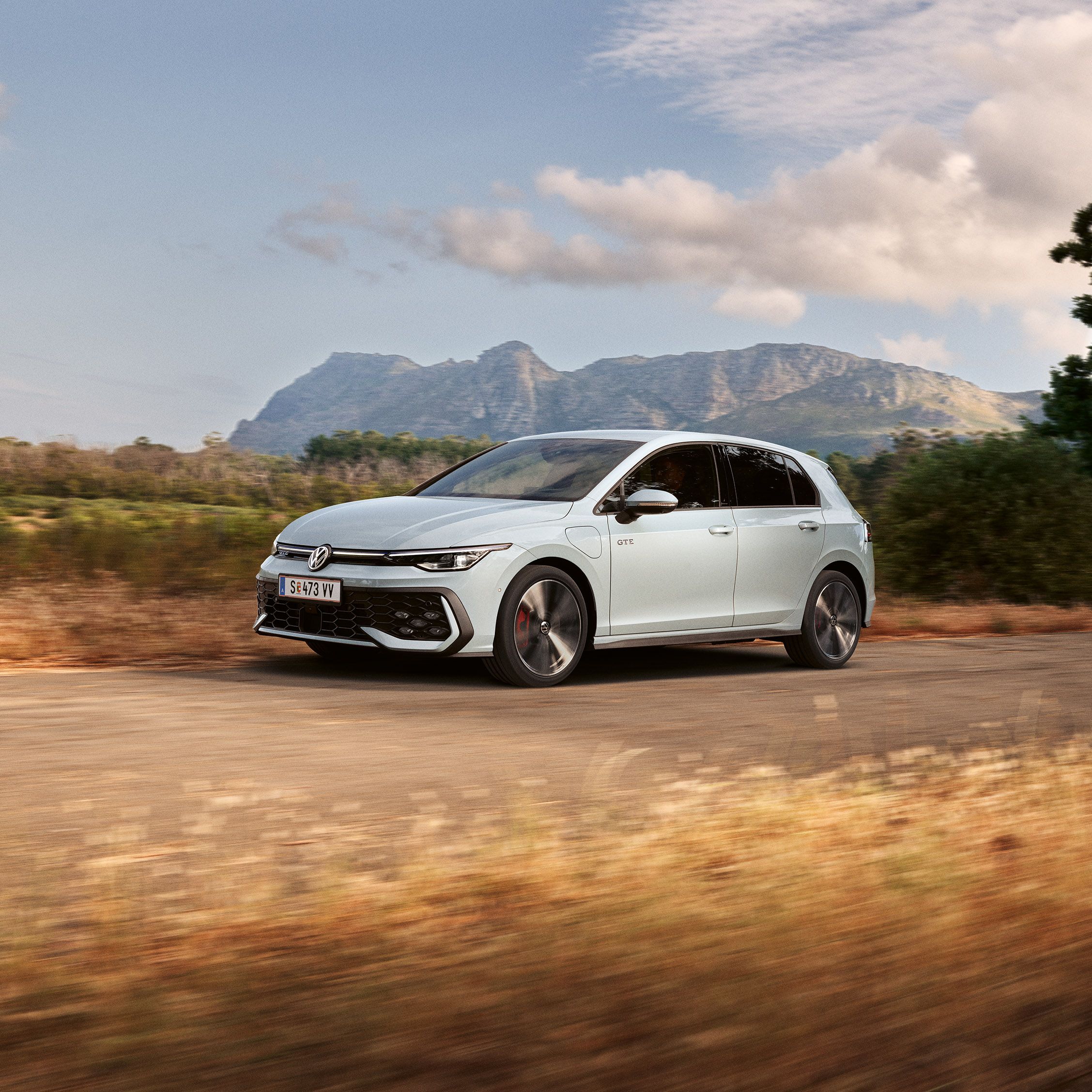 Der VW Golf GTE fährt auf einer Landstraße, im Hintergrund sieht man Berge
