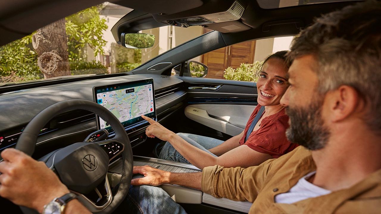 Ein Mann und eine Frau sitzen im VW, sie zeigt auf den Navi-Bildschirm