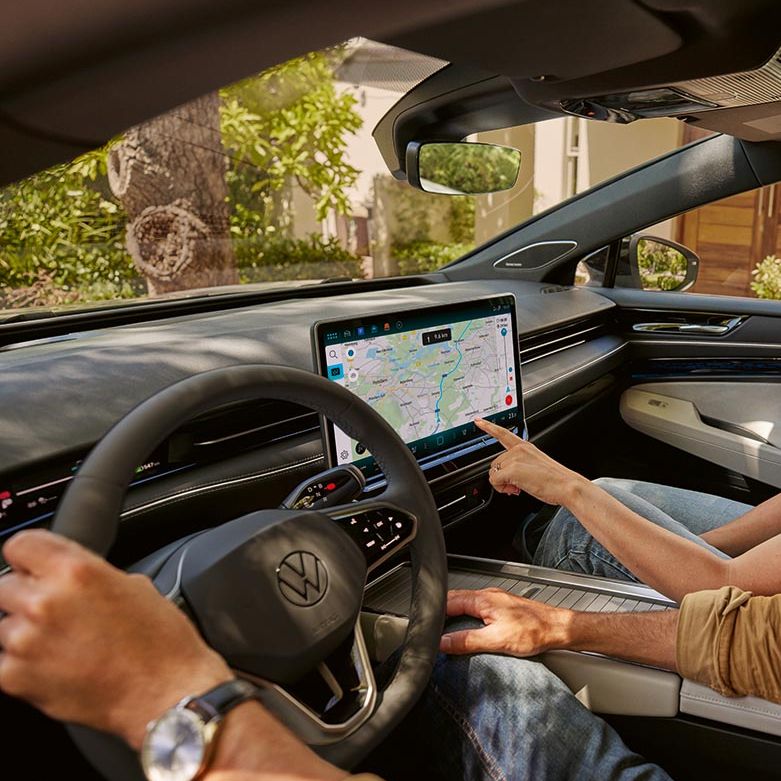 Ein Mann und eine Frau sitzen im VW, sie zeigt auf den Navi-Bildschirm