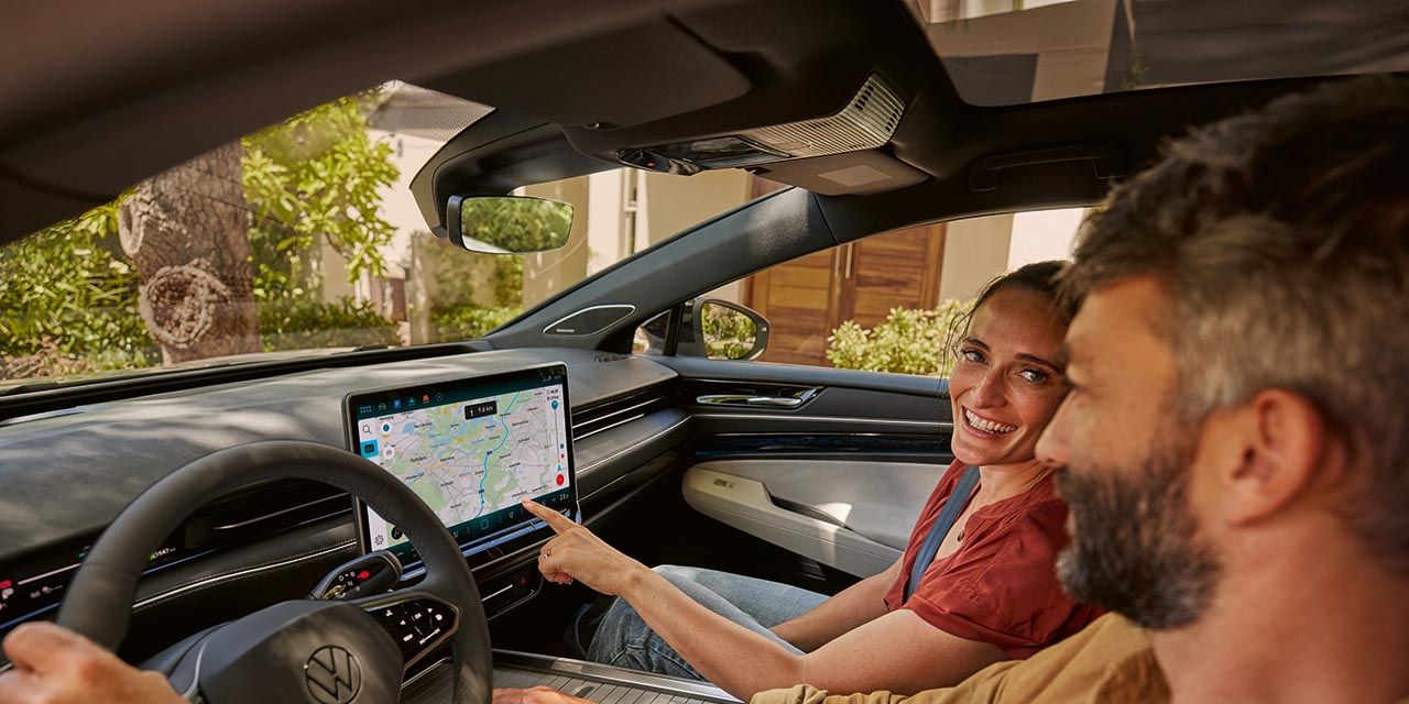 Ein Mann und eine Frau sitzen im VW, sie zeigt auf den Navi-Bildschirm