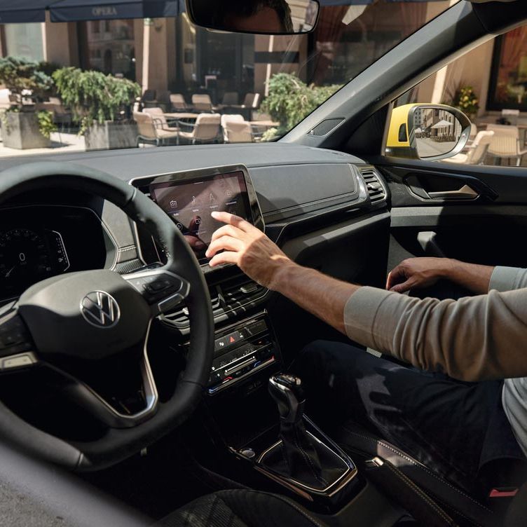 Ein Mann bedient vom Beifahrersitz aus den Bildschirm des VW T-Cross