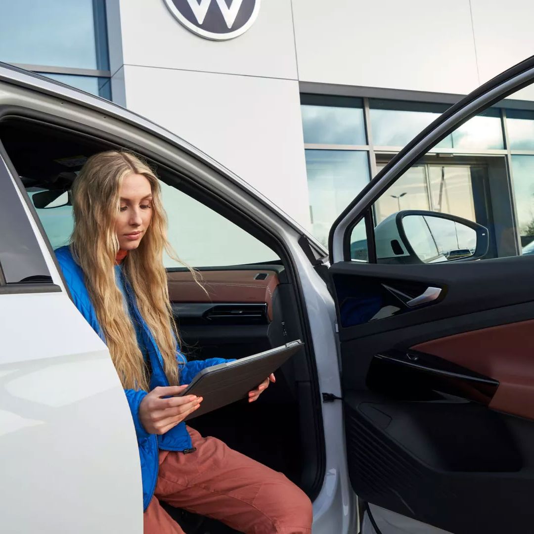 Eine Frau sitzt bei geöffneter Autotüre in einem VW ID.