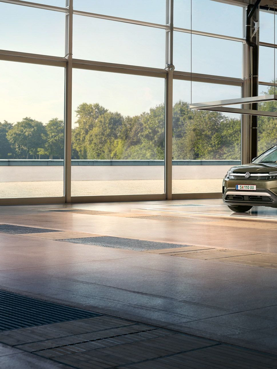 Ein VW ID. Cross steht in einem minimalistisch eingerichteten Designstudio, daneben tänzelt ein aufgeregter Mann und unterhält sich mit einer Ingenieurin.