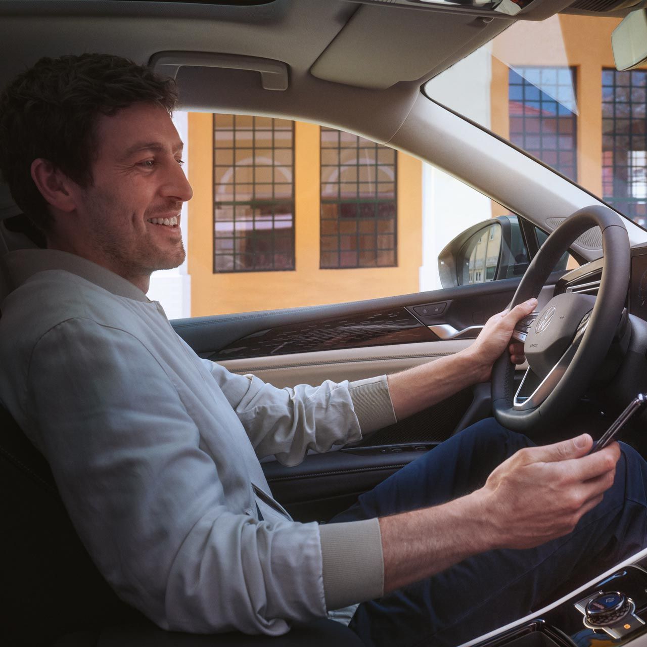 Mann sitzt in VW Tiguan und hält Smartphone in der Hand