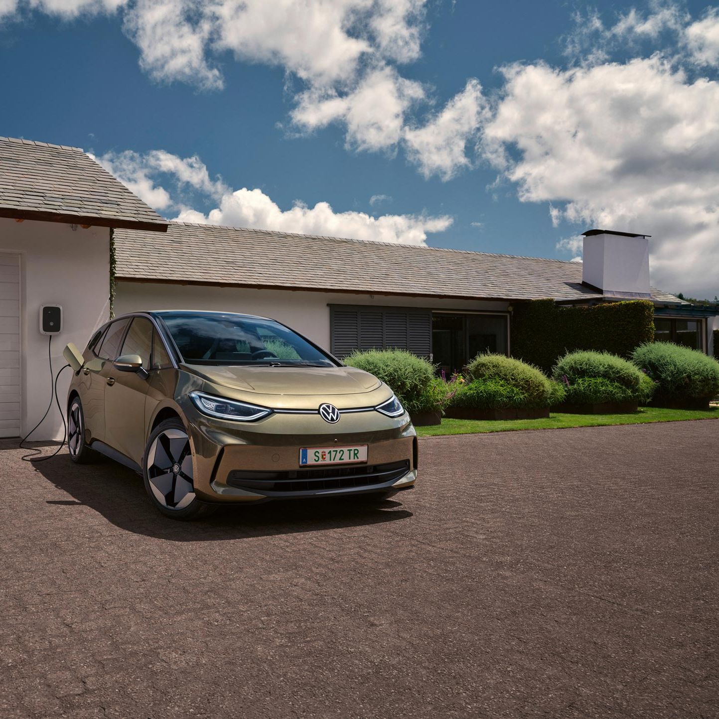 Der VW ID.3 wird an einer Wallbox geladen im Hintergrund ein Einfamilienhaus