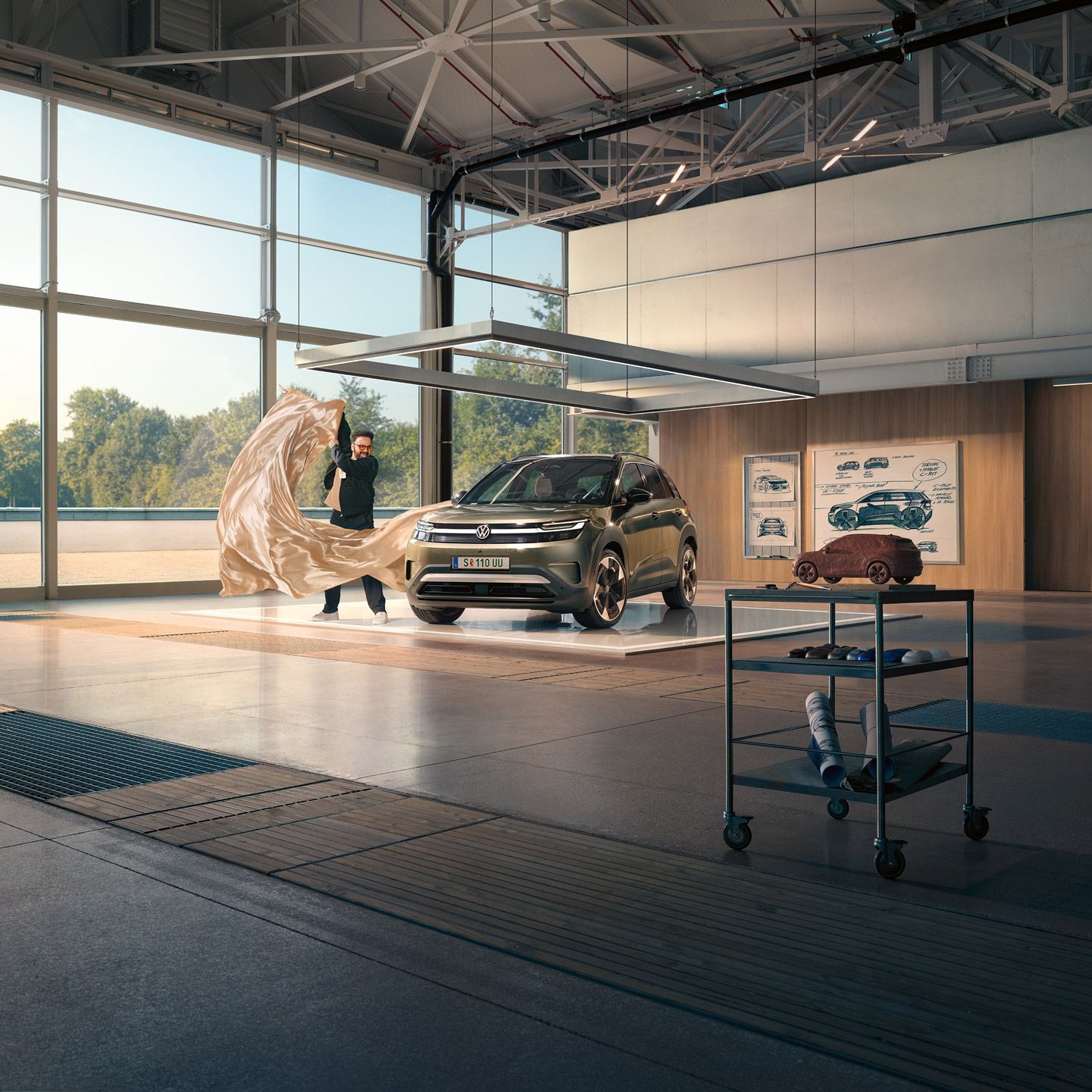 Ein Mann zieht ein großes Tuch von einem grünen VW ID. Cross, der in einem minimalistisch eingerichteten Designstudio steht.