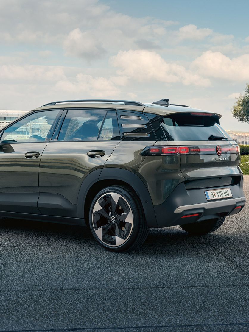 Heckansicht eines grünen VW ID. Cross, der auf einem Platz mit grünen Bäumen parkt.