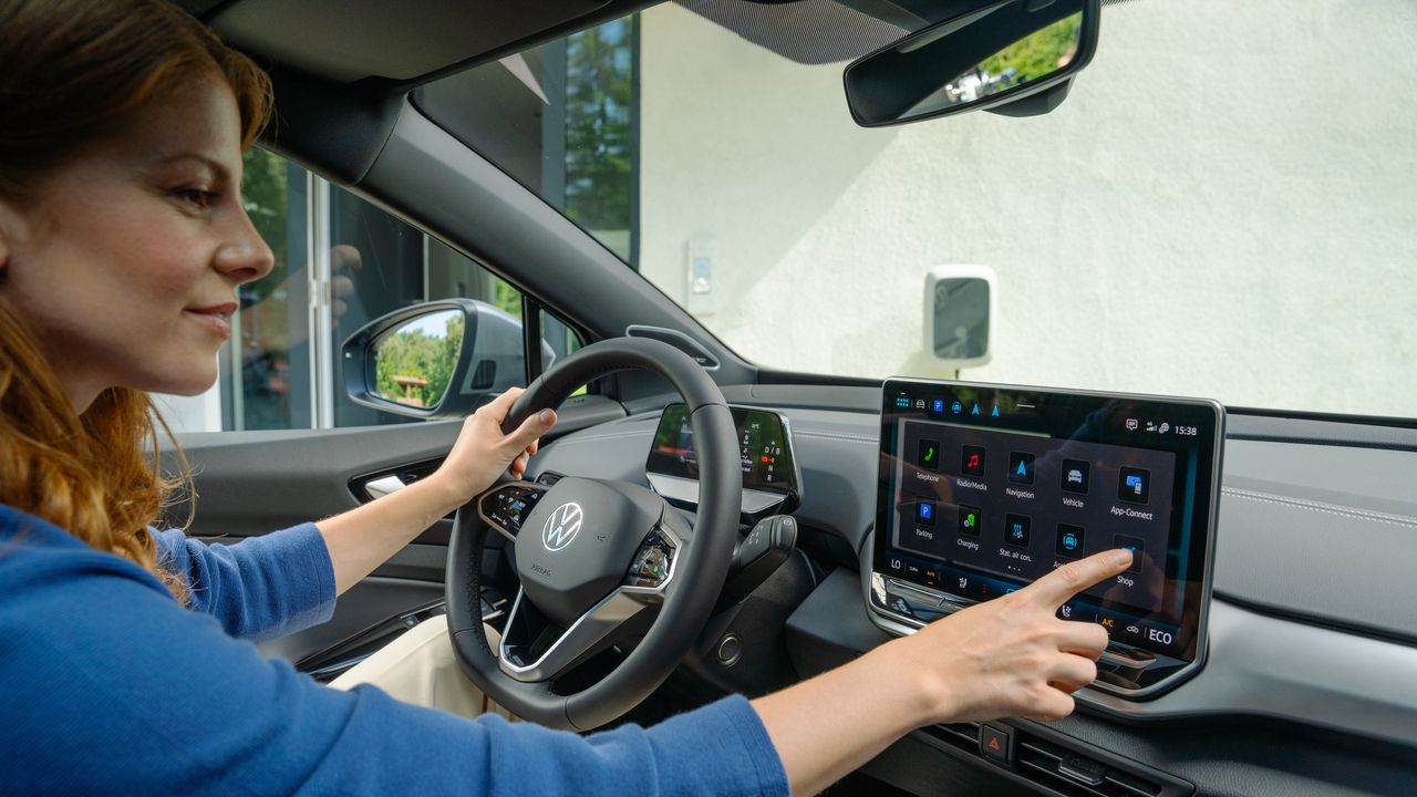 Innenansicht des ID.5. Eine Frau sitzt auf dem Fahrersitz und bedient das Infotainmentsystem.