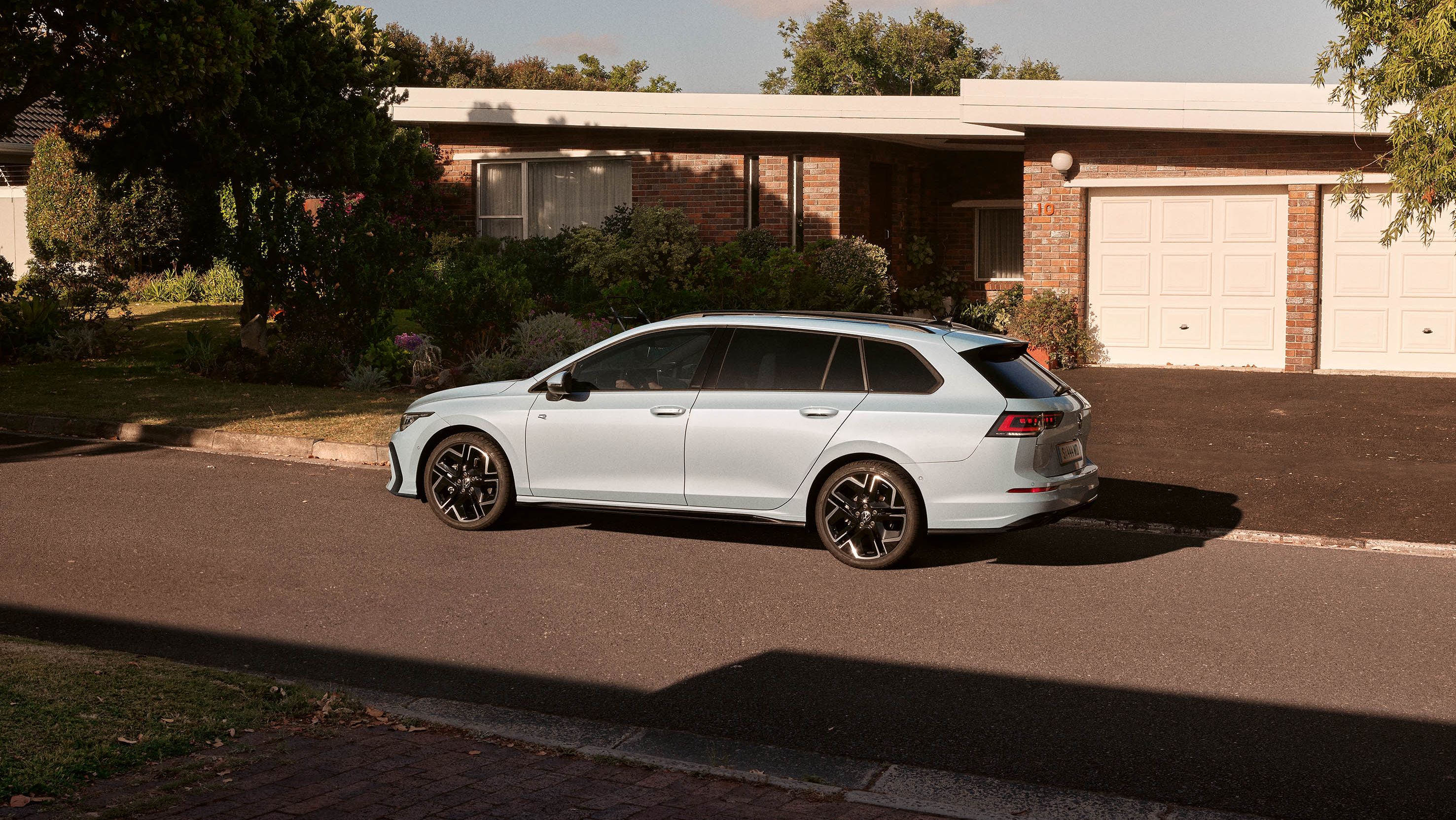 Seitenansicht eines VW Golf Variant in der Farbe Ice Blue Metallic geparkt vor Einfamilienhaus