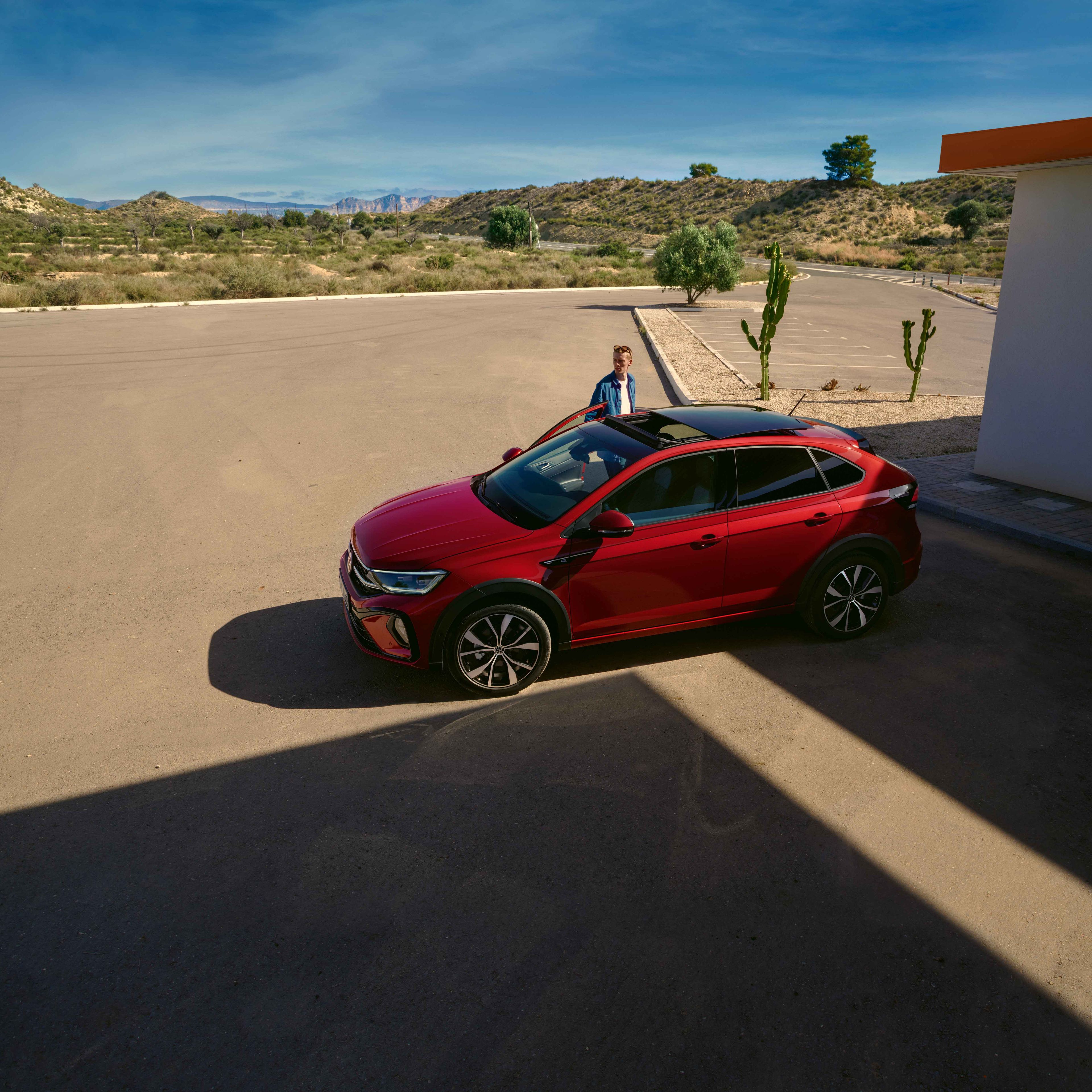 Seitenansicht eines roten VW Taigo R-Line, Mann öffnet Beifahrertür