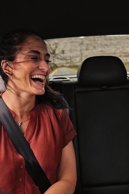 2 Peronen sitzen auf der Rückbank eines Volkswagen und schauen lächelnd auf ein Mobiltelefon