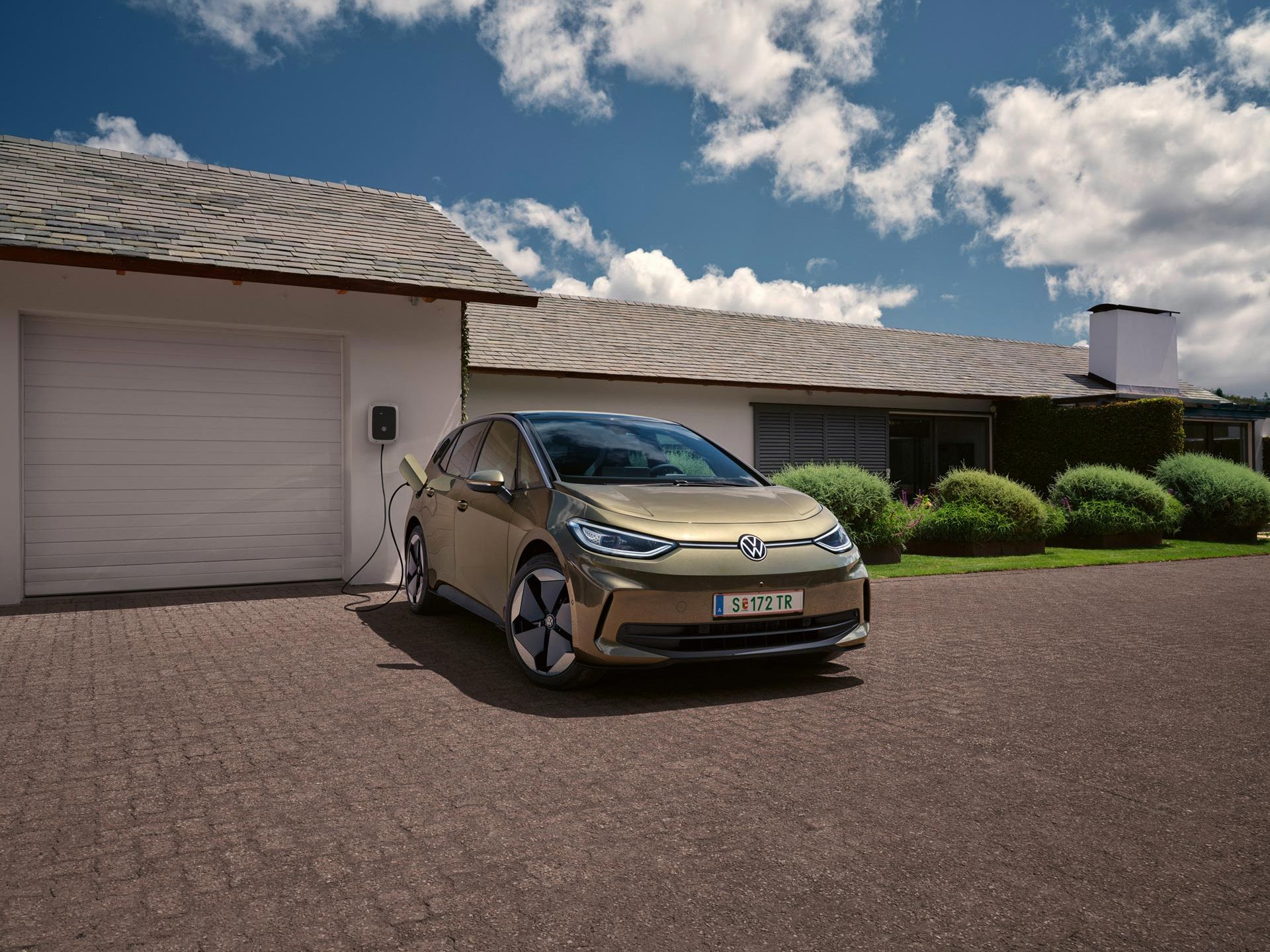 Der VW ID.3 wird an einer Wallbox geladen im Hintergrund ein Einfamilienhaus