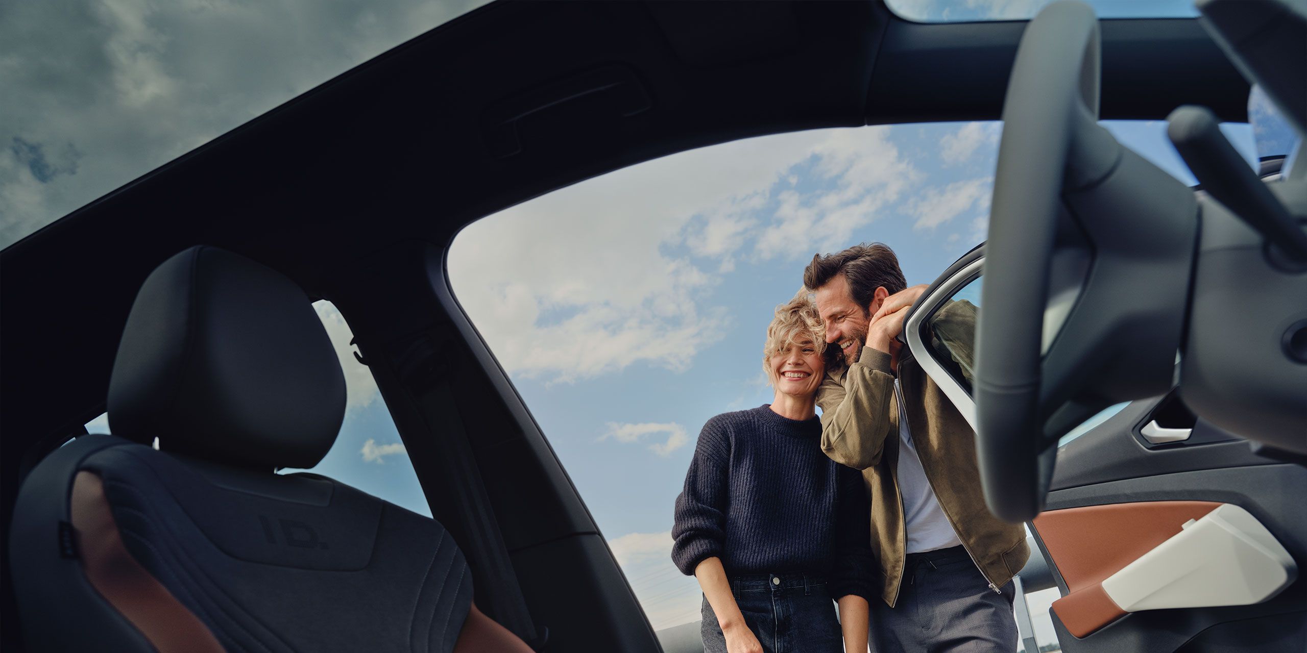 Paar steht glücklich vor Auto