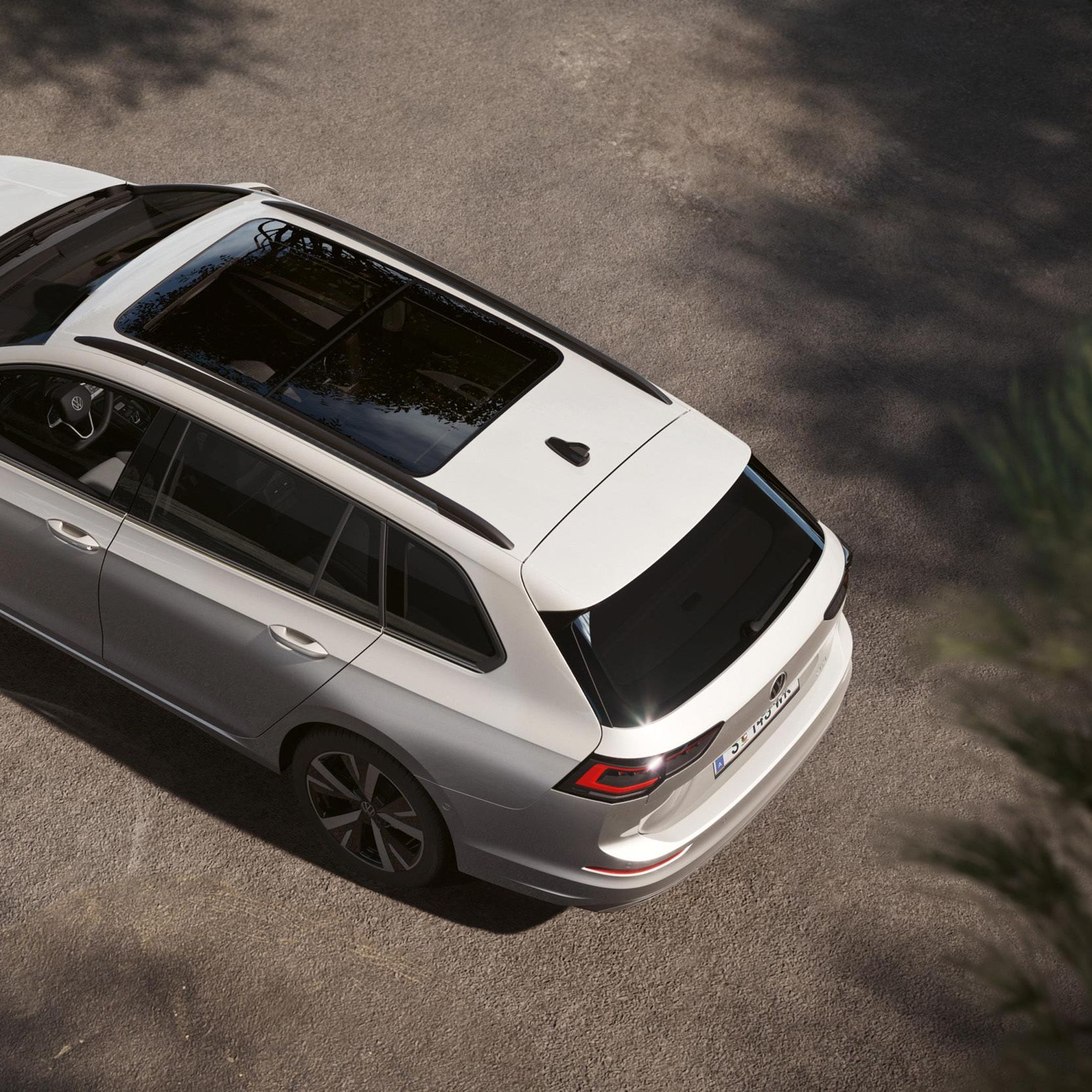 Ein weißer VW Golf Variant mit Panoramadach aus der Vogelperspektive, von oben