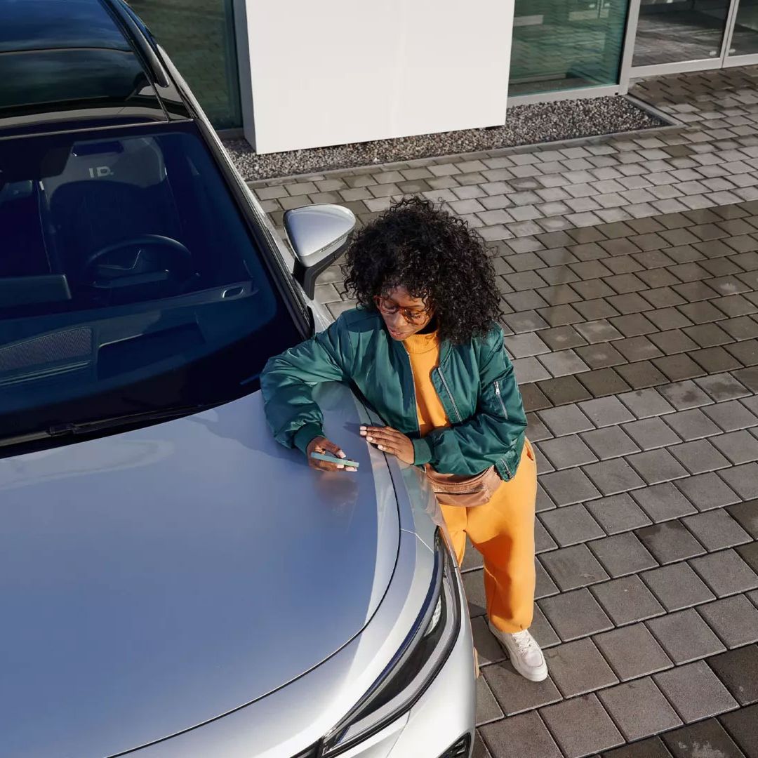 Ein VW ID. mit Blick von oben, eine Frau lehnt an der Kühlerhaube