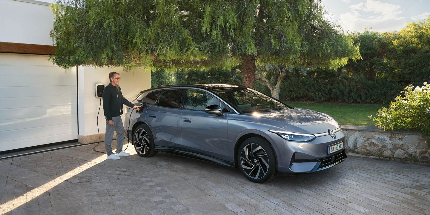Mann lädt seinen VW ID.7 Tourer über eine Wallbox vor seiner Garage