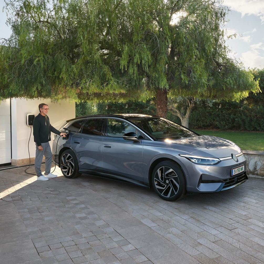 Mann lädt seinen VW ID.7 Tourer über eine Wallbox vor seiner Garage