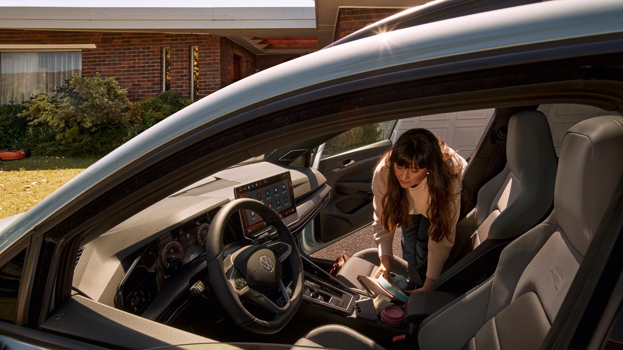 Blick in den Innenraum des VW Golf Variant, Frau beugt sich auf der Beifahrerseite ins Auto