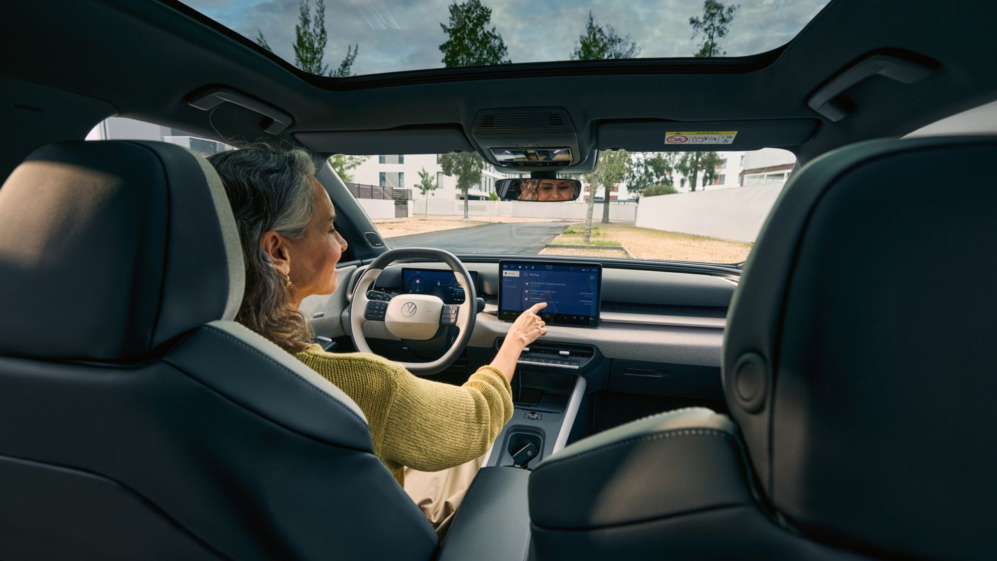 Eine Frau sitzt auf dem Fahrersitz eines VW ID. Cross und bedient das Infotainment-System.