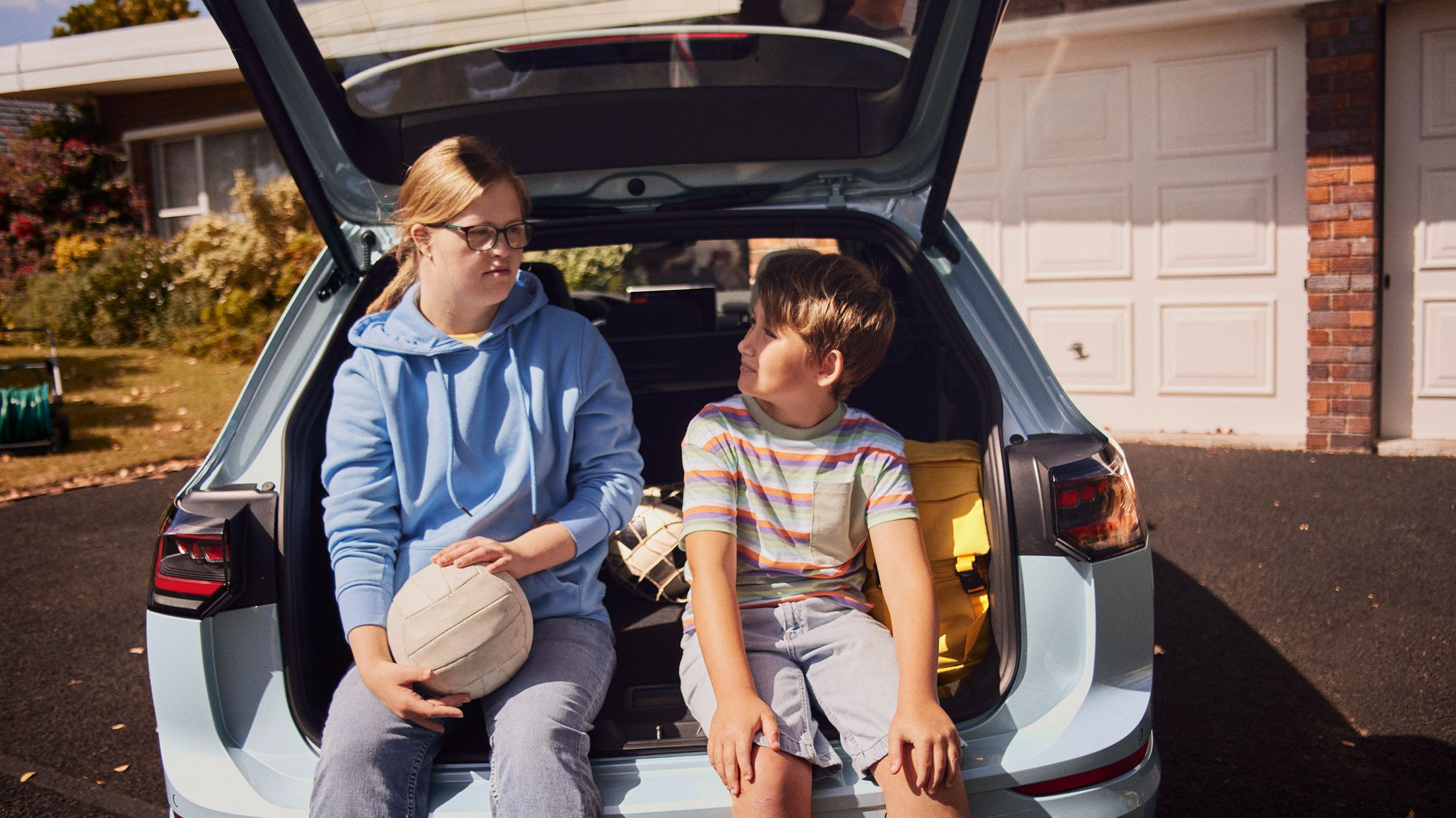 Junge und Mädchen sitzen im Kofferraum des VW Golf Variant