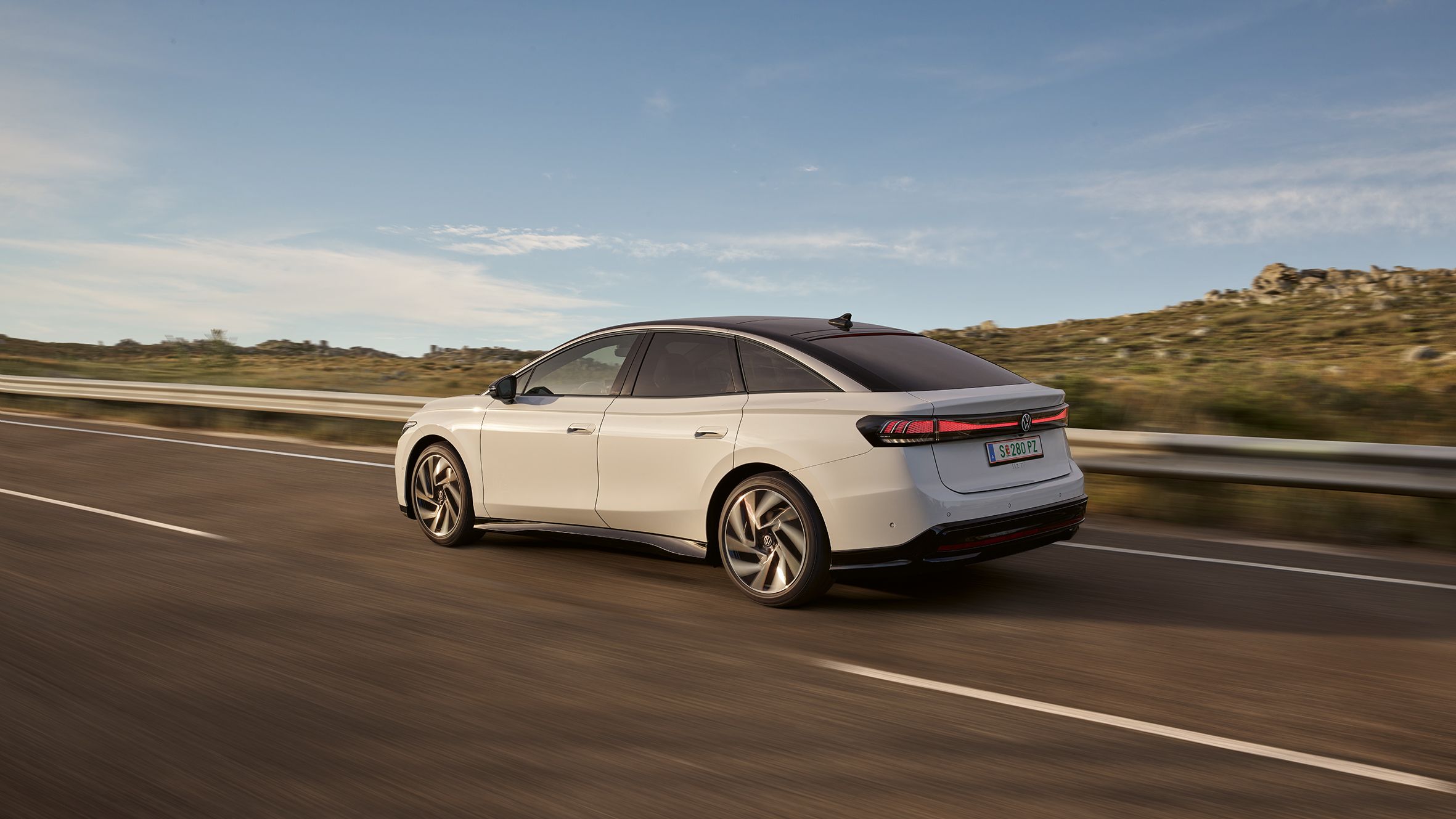 Heckansicht eines weißen VW ID.7 der auf Landstraße fährt