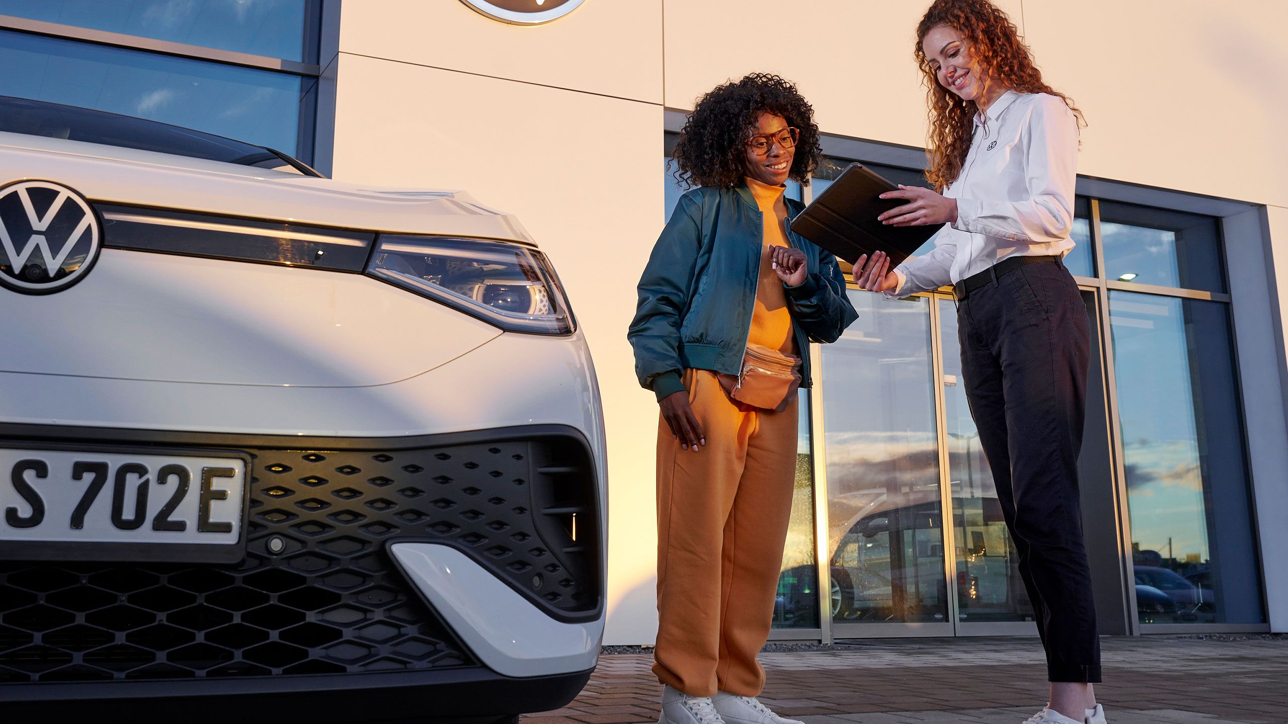 Eine VW Service MItarbeiterin mit einer Kundin vor einem Volkswagen Servicebetrieb
