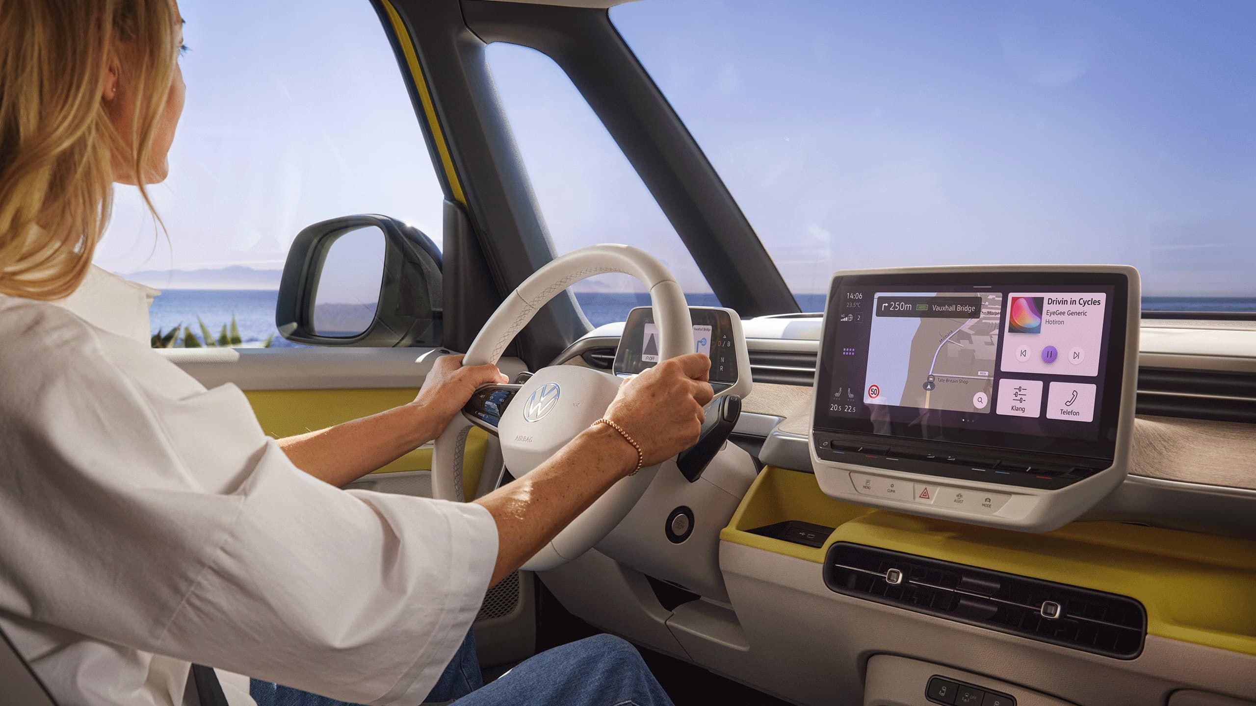 Eine Frau sitzt am Steuer des VW ID. Buzz, ihre Hände sind am Lenkrad des Elektro-Vans.