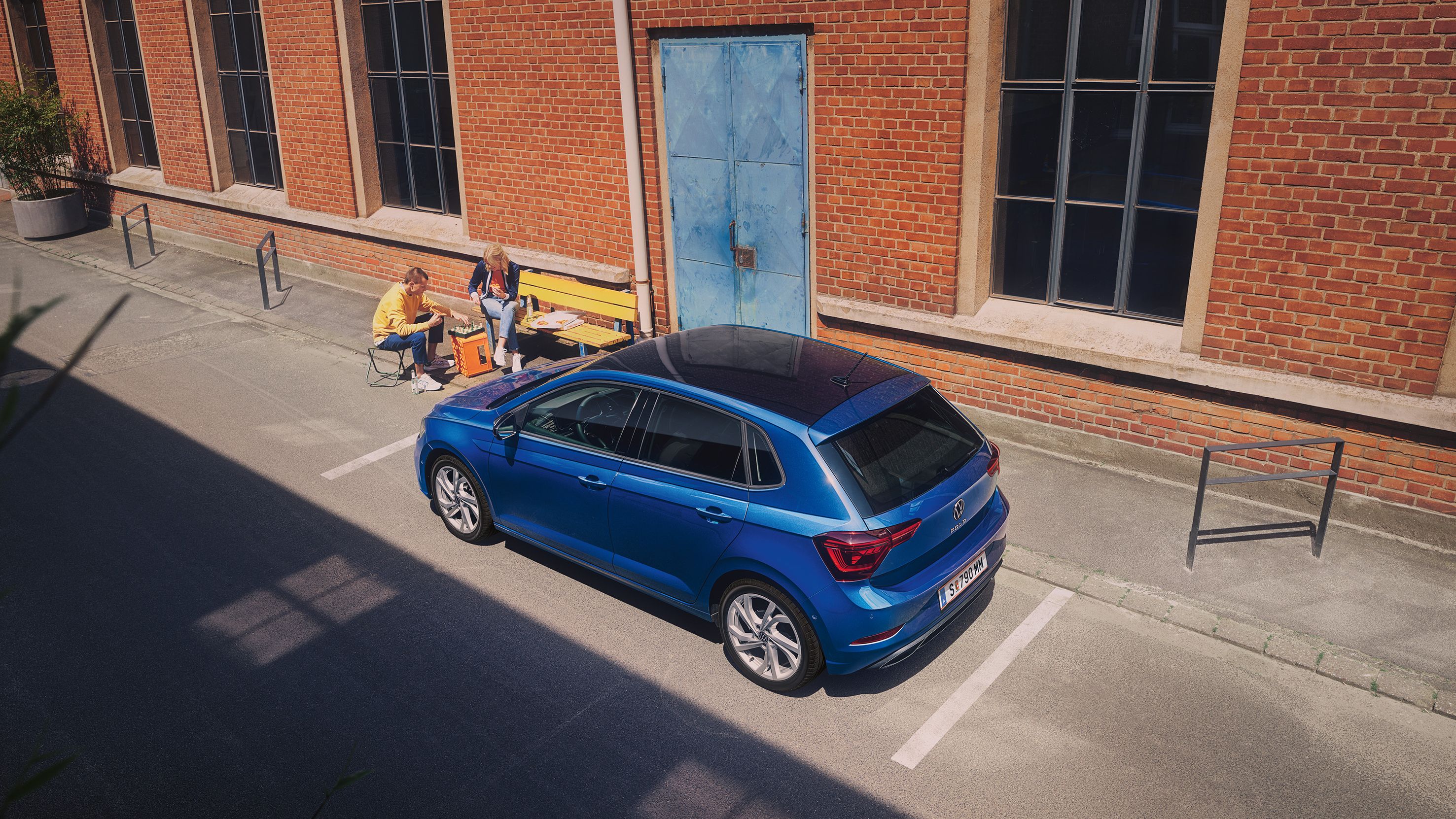 Blick von oben auf einen blauen VW Polo R-Line der vor Industriegebäude geparkt ist