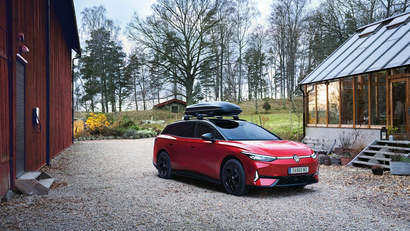 Ein roter VW ID.7 Tourer GTX mit Dachbox in ländlicher Umgebung