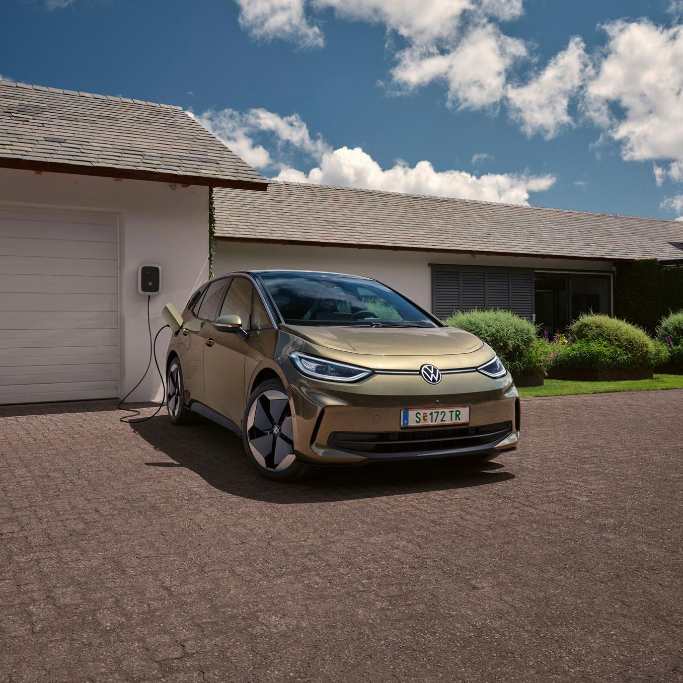 Der VW ID.3 wird an einer Wallbox geladen im Hintergrund ein Einfamilienhaus
