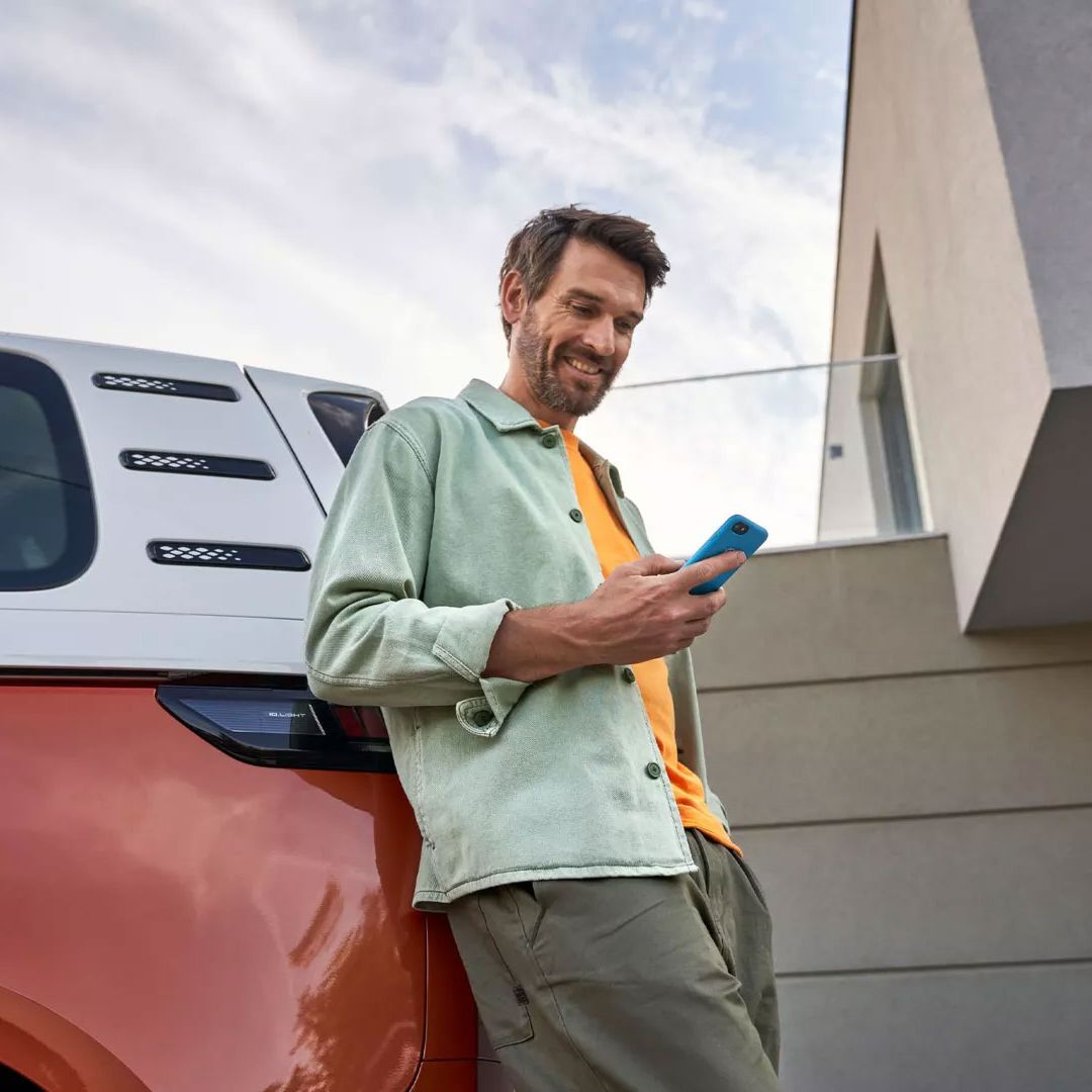 Im Mann mit Smartphone lehnt an einem ID. Buzz
